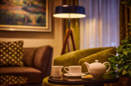 Teetasse auf dem Nachttisch und im Hintergrund eine brennende Lampe