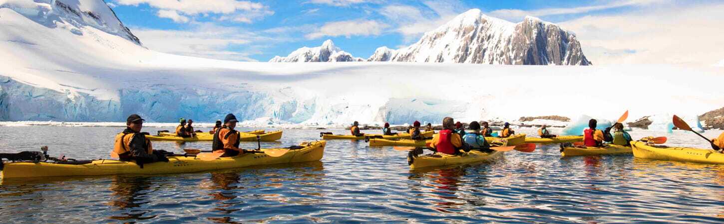 landscape image of a kayaking group next to glaciers