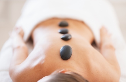 woman laying down with hot rocks on back