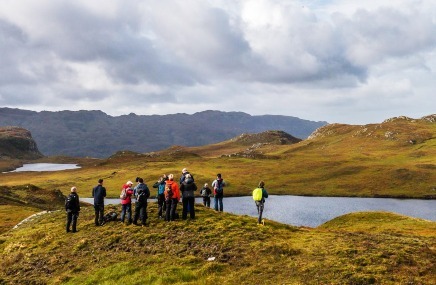 Un grupo de excursionistas contemplando un lago con las montañas al fondo