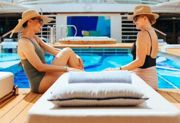 Zwei Frauen, die sich am Pool anlächeln