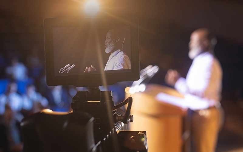 camera recording man speaking at a podium